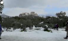 Gli abitanti di Atene si divertono con la neve sulle colline davanti all'Acropoli