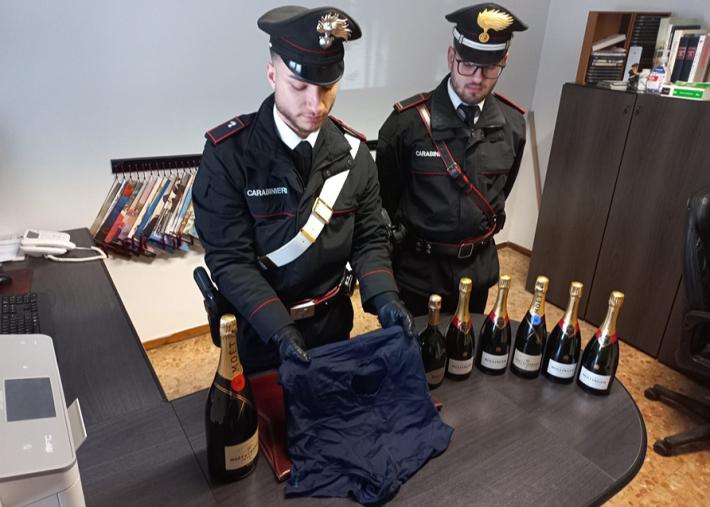 Ruba lo champagne nascondendo le bottiglie in una panciera sotto i vestiti