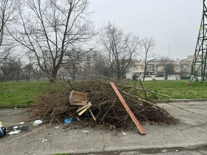 Cataste di legna e rifiuti in largo Emilio Lussu lungo via Budellungo