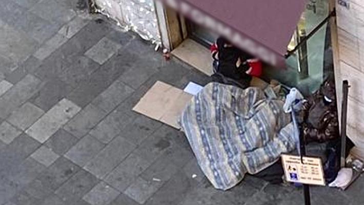 Senzatetto dorme davanti a negozio